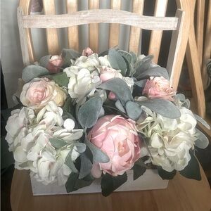 Floral arrangement of pink & white flowers with/ green petals in white basket.